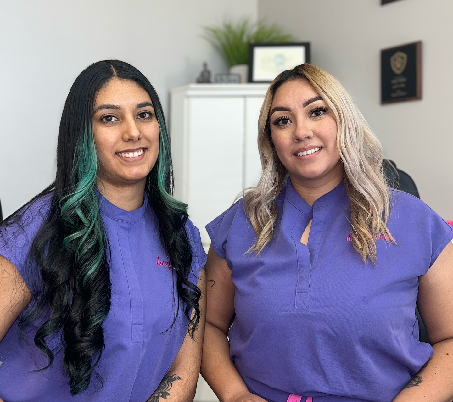 two daisy maids team members in purple uniforms smiling at the office